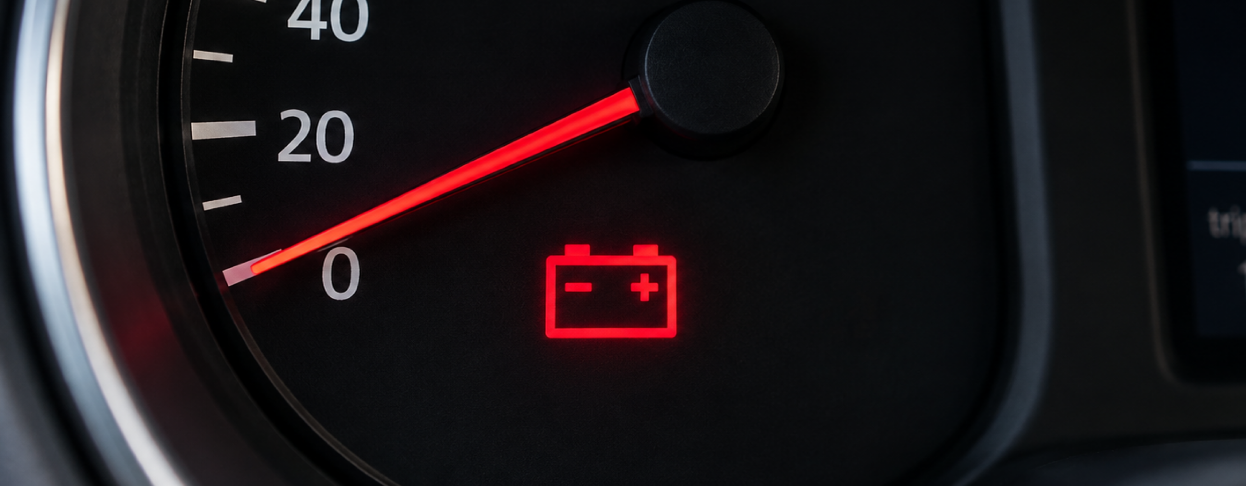 Breed dashboardbeeld met een brandend accuwaarschuwingslampje, gebruikt als bannerafbeelding bij het blog over auto-accu's